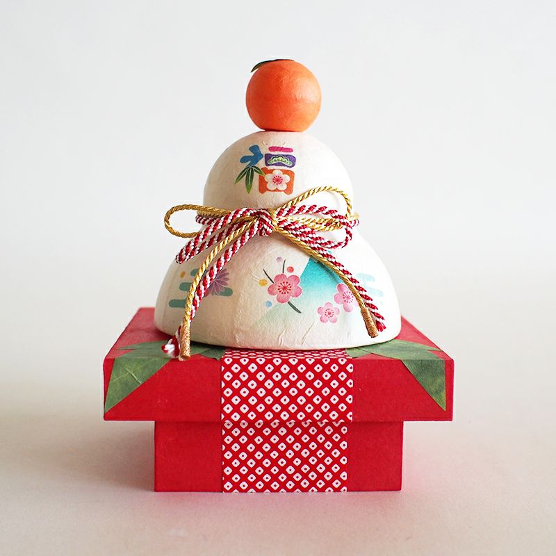 ちぎり和紙で作られた鏡餅から、福を呼ぶ五つの縁起物が顔を出す、ユニークでかわいらしいデザインです。