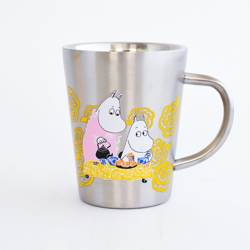 ムーミンママがポットから紅茶を注ぎ、ムーミンが嬉しそうにパンを食べている姿が描かれています